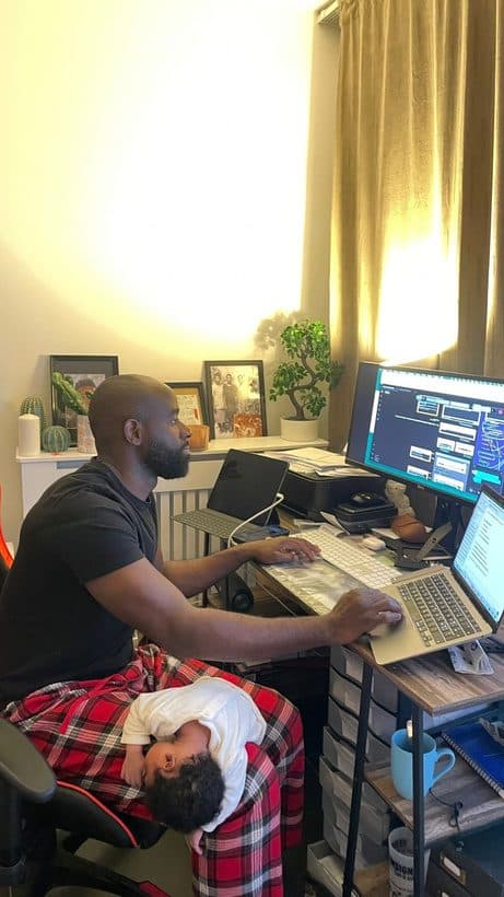 Cédrick travaille à son bureau, un enfant endormi sur ses genoux